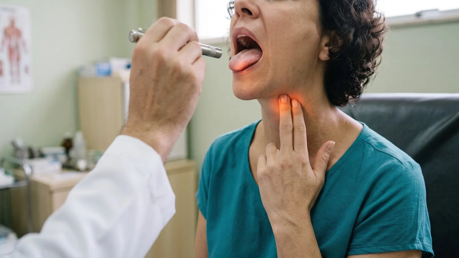 Na consulta, uma mulher mostra ao médico, com a ponta de dois dedos, o lugar embaixo da mandíbula onde fica a glândula submandibular.
