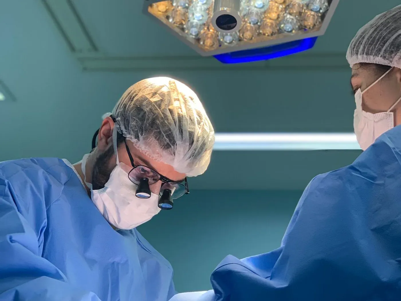 Dr. Stéfano Fiúza operando com lupa cirúrgica e fotóforo
